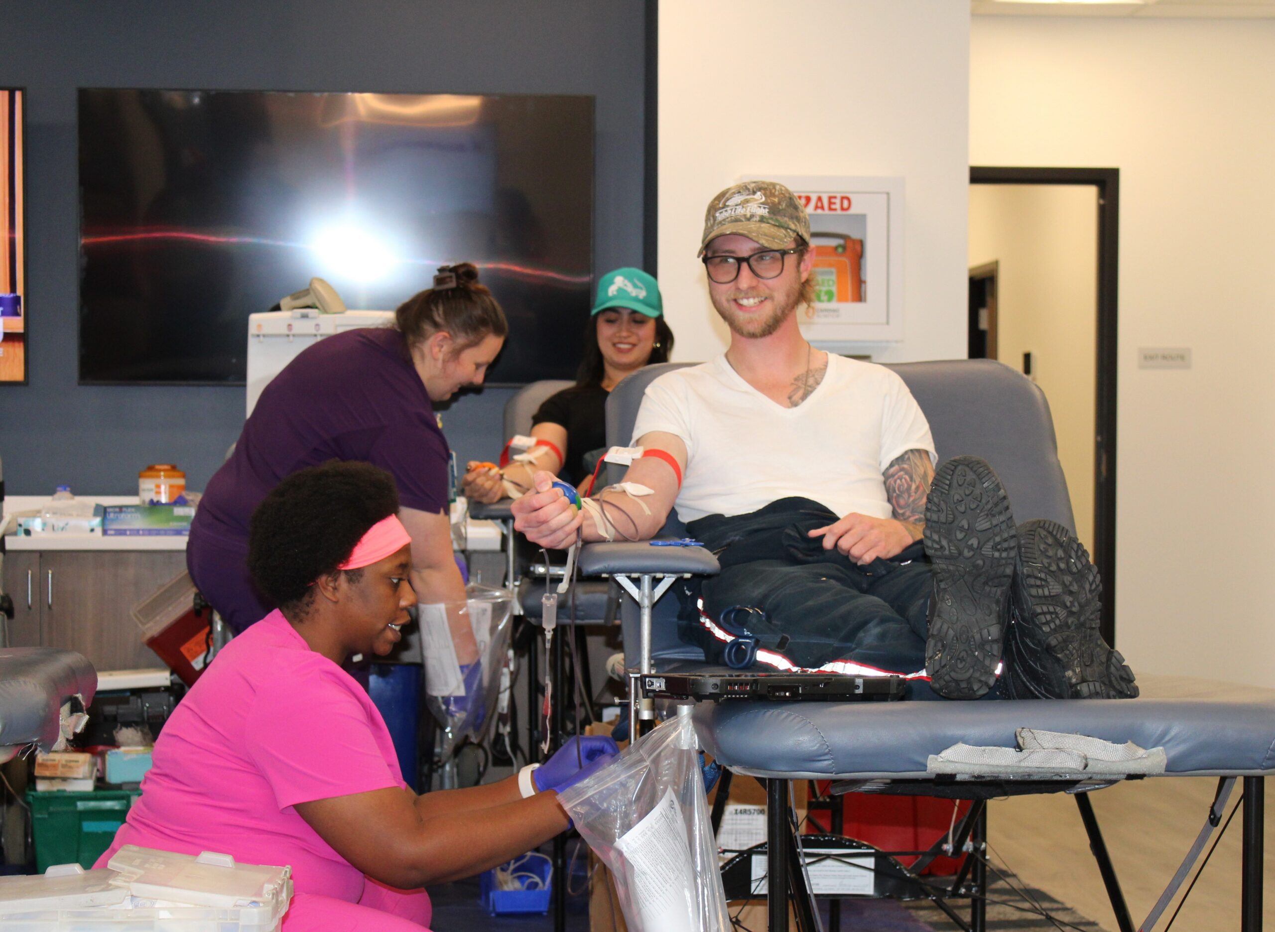 Nurse kneels near man donating blood.